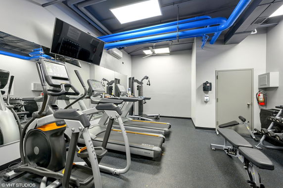 Indoor gym area with various fitness equipment including treadmills and benches.
