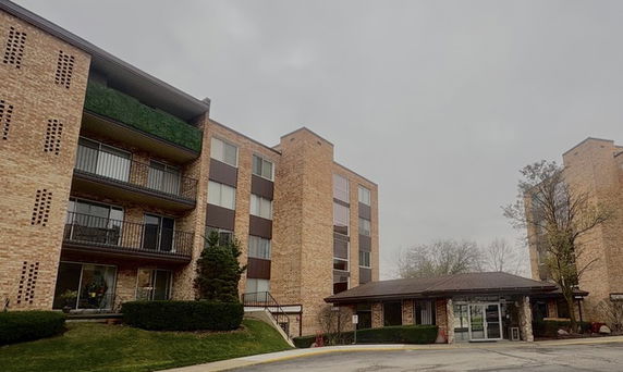 Front view of a multi-story brick apartment building with balconies.