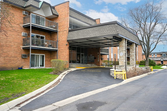 Front view of a multi-story brick building with balconies and a covered entrance.