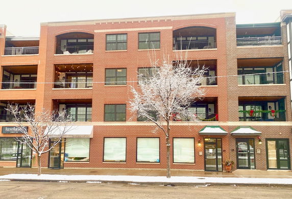 Front view of a multi-story brick building with balconies and large windows.