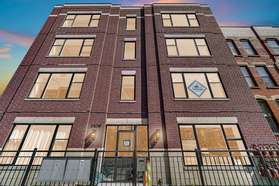 Front view of a multi-story brick building with large windows.