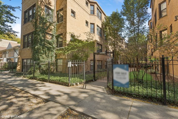 Front view of a multi-story brick building with gated entrance.