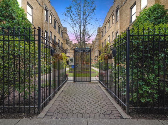 Front view of a multi-story brick building with an iron gate entrance.