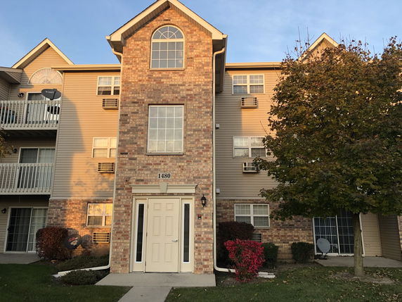 Front view of a multi-story residential building with brick and siding facade.