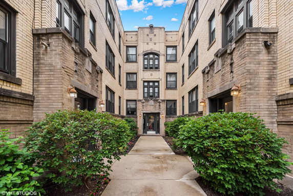 Front view of a multi-story brick apartment building with a central entrance.