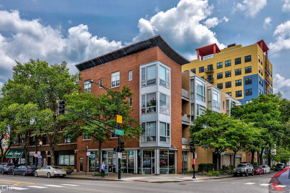 Front view of a multi-story urban building with commercial spaces on the ground floor.