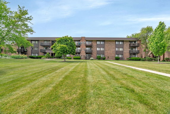 Front view of a three-story brick apartment building with balconies.