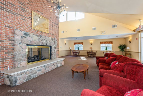 Interior view of a clubhouse with red sofas and a stone fireplace.