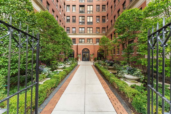 Front view of a multi-story brick building with an entrance pathway and garden.