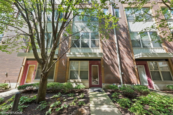 Front view of a multi-story brick building with large windows and red doors.