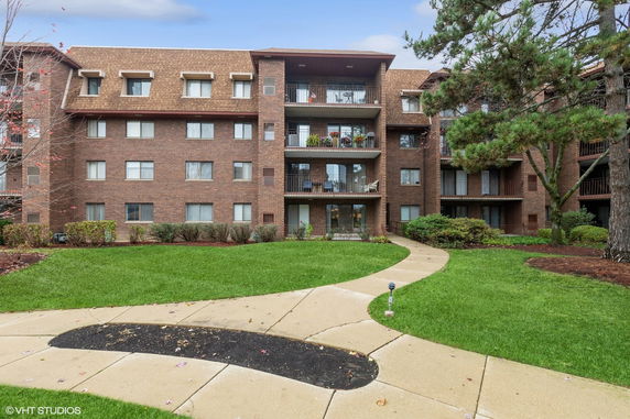 Front view of a multi-story brick apartment building with balconies.