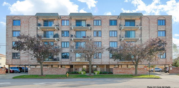 Front view of a multi-story brick apartment building with balconies.