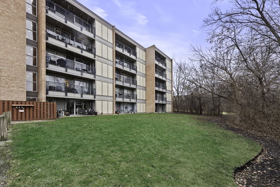 Front view of a multi-story apartment building with balconies and brick exterior.