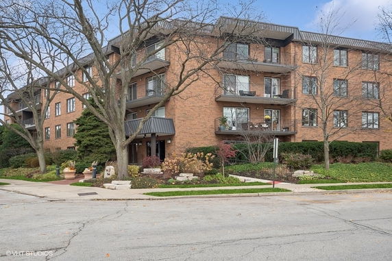 Front view of a four-story brick apartment building with balconies.