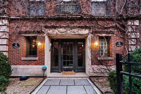 Front view of a building with brick facade and vine-covered walls.