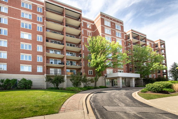 Front view of a multi-story brick apartment building with balconies.
