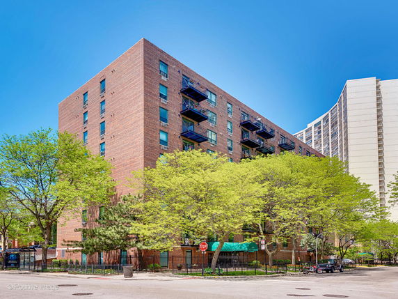 Front view of a multi-story brick apartment building with balconies and large windows.