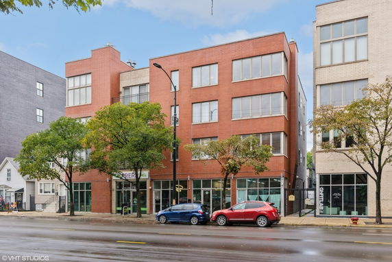 Front view of a multi-story brick building with large windows.