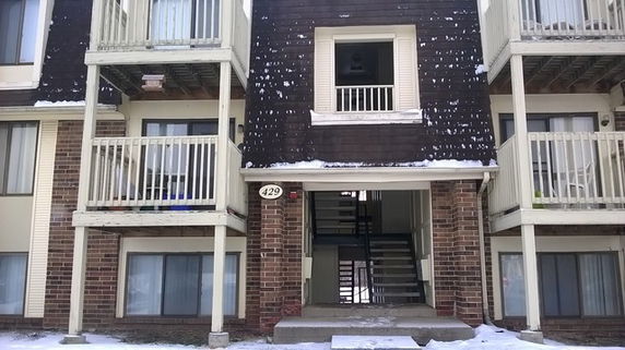 Front view of a multi-story building with balconies and a central staircase entrance.