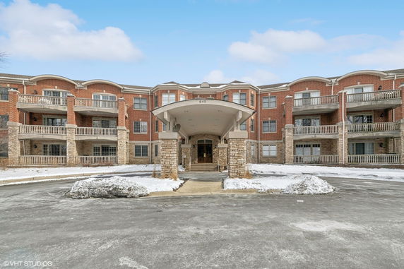Front view of a multi-story brick building with balconies and a covered entrance.