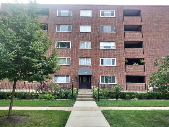 Front view of a multi-story brick apartment building with balconies.