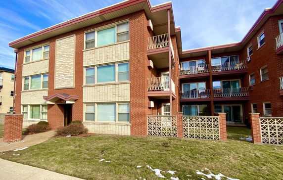 Front view of a three-story brick apartment building with multiple balconies.