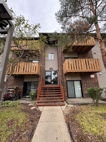 Exterior view of a multi-story residential building with brick facade and wooden balconies.