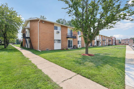 Front view of a multi-story brick apartment building with balconies.
