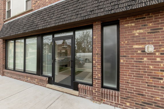 Front view of a red brick building with large windows and a glass door.