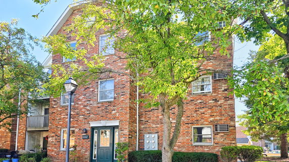 Front view of a multi-story brick building with several windows and a green door.