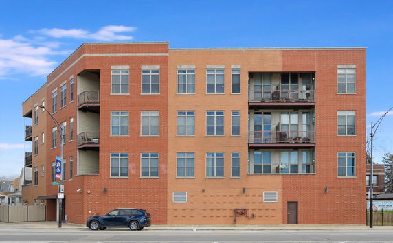 Front view of a multi-story brick apartment building with balconies.