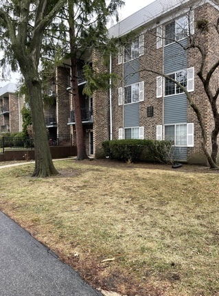 Front view of a multi-story apartment building with brick and siding exterior.