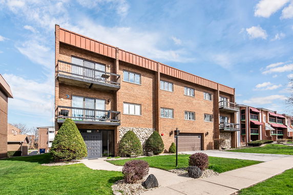 Front view of a multi-story brick building with balconies and a garage.