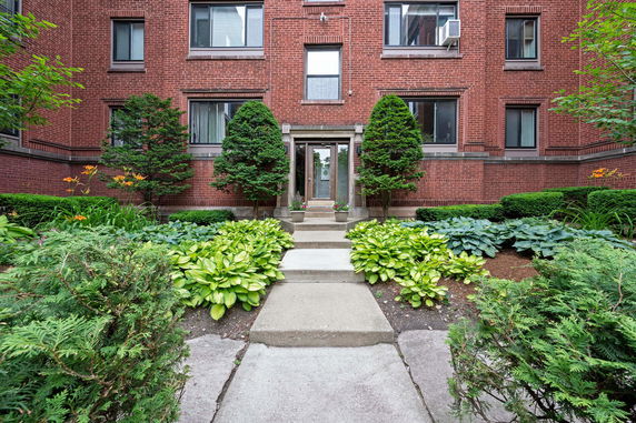Front view of a brick building entrance with symmetrical landscaping.
