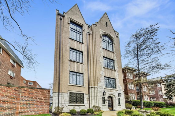 Front view of a multi-story brick building with large windows and decorative masonry.