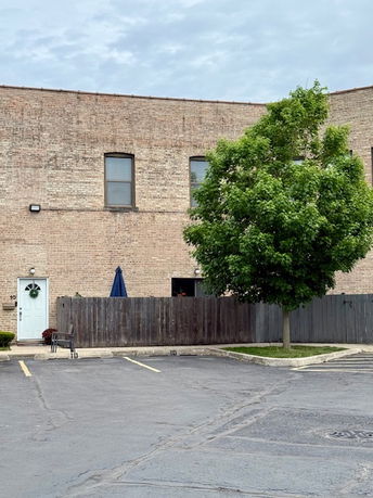 Front view of a two-story brick building with a fenced area and parking spaces.