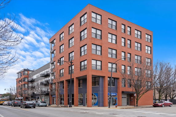 Front view of a multi-story brick building with large windows.