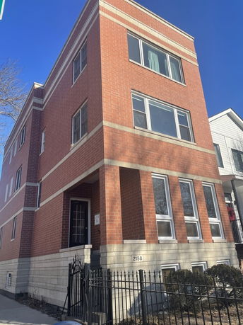 Front view of a three-story brick building with large windows.