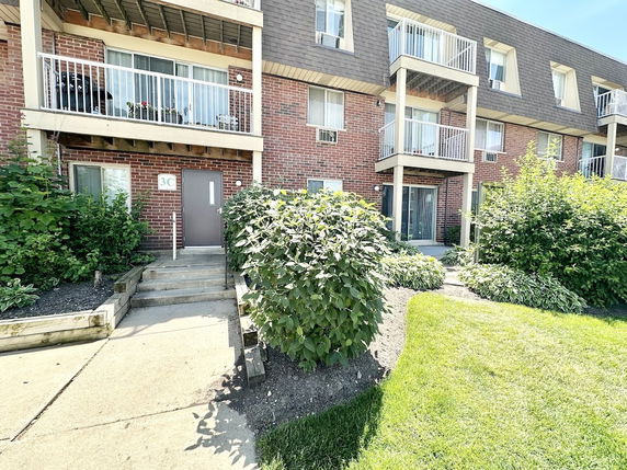 Front view of a multi-story brick apartment building with balconies.