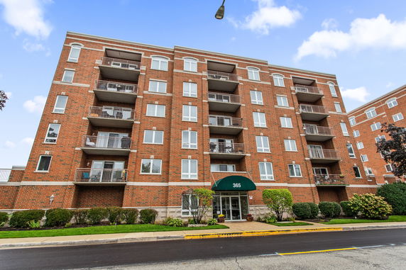 Front view of a multi-story brick apartment building with balconies.