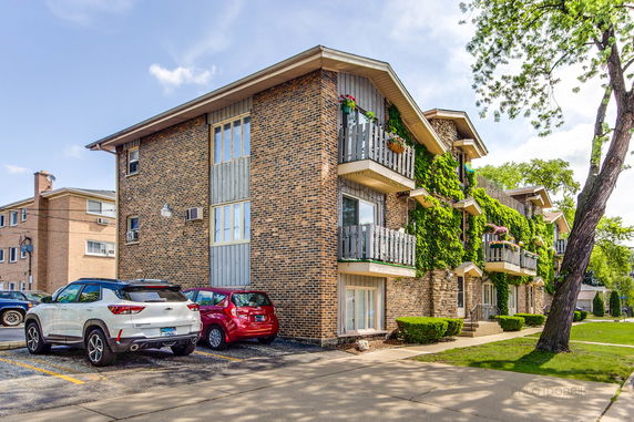 Front view of a multi-story apartment building with balconies clad in brickwork.