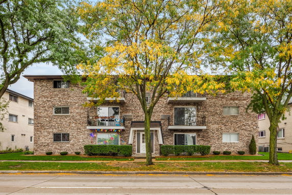Front view of a three-story apartment building with brick facade and balconies.