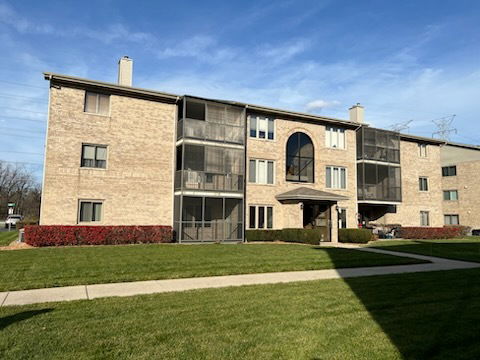 Front view of a multi-story apartment building with brick exterior and balconies.