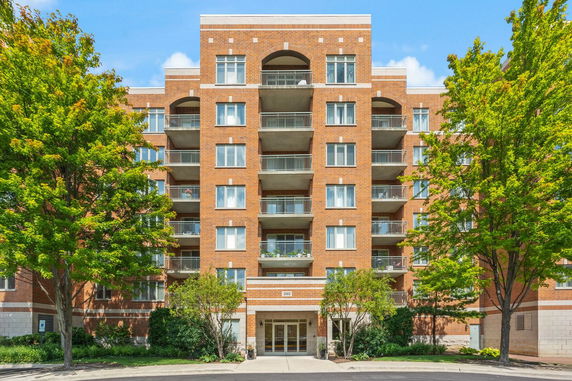 Front view of a multi-story brick building with balconies and a central entrance.