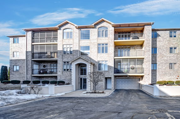 Front view of a multi-story apartment building with balconies and a garage entrance.