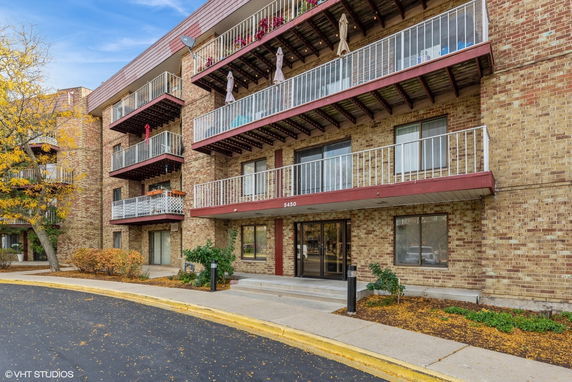 Front view of a multi-story residential building with balconies and a brick facade.