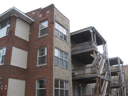 Front view of a multi-story brick apartment building with balconies.