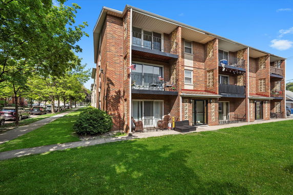 Front view of a multi-story brick apartment building with balconies.