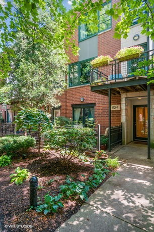 Front view of a brick building with a balcony and plants.