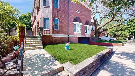Front view of a multi-story brick house with stairs leading to the entrance.